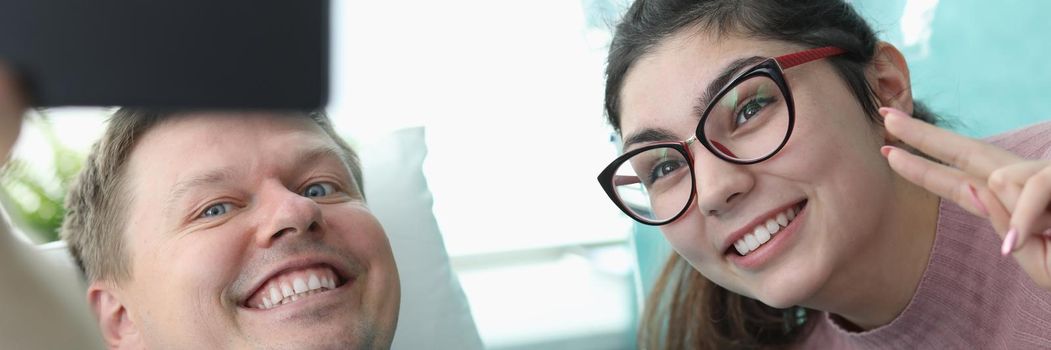 Portrait of smiling young woman and hospital patient taking selfie on mobile phone. Cheerful family picture. Modern clinic room for sick people. Medicine and recovery concept