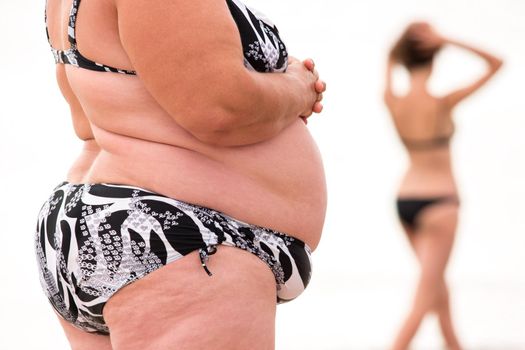 Fat woman and slim girl. Female bodies isolated. Appearance is reflection of lifestyle. Fitness versus obesity.