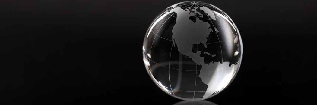 Closeup of glass globe on black background. Screensaver for world news concept