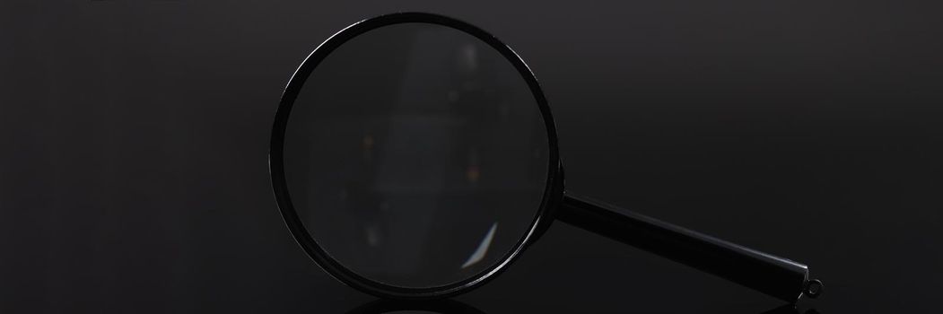 Closeup of magnifying glass on black background. Hyperopia treatment concept