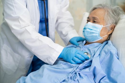 Doctor using stethoscope to checking Asian senior or elderly old lady woman patient wearing a face mask in hospital for protect infection Covid-19 Coronavirus.