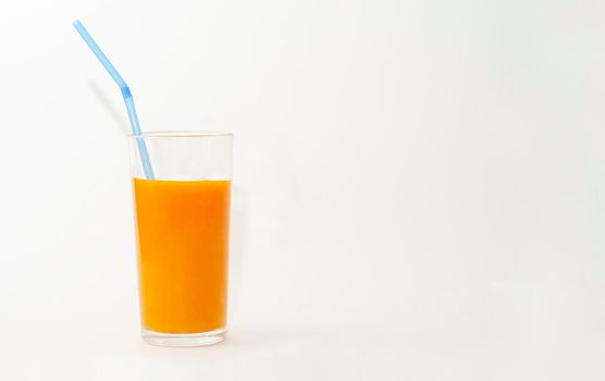a glass of pumpkin juice with blue straw on white background, copy space.