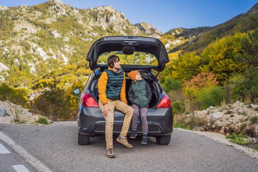 Dad and son are resting on the side of the road on a road trip. Road trip with children concept.