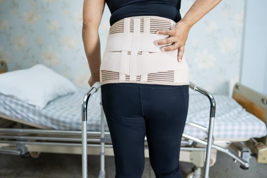 Asian lady patient wearing back pain support belt for orthopedic lumbar with walker.