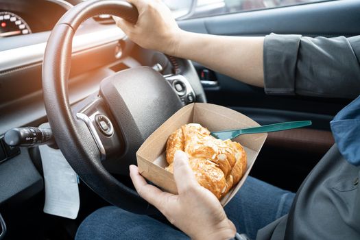 Asian lady holding bread bakery food in car, dangerous and risk an accident.
