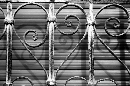 Window with forged metal lattice with curved details and wooden blind