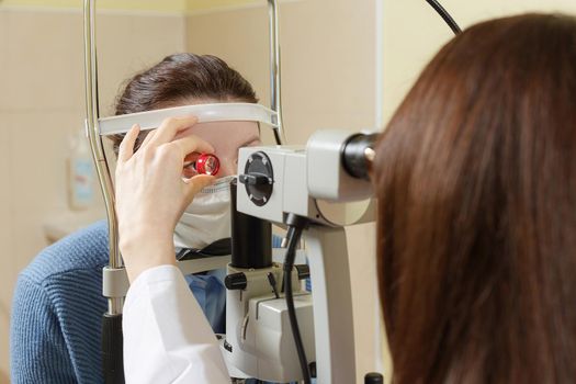 Female doctor checks the female patient through the magnifying glass