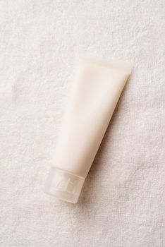 Mockup facial skincare product white tube with blank label on farbic background, Top view