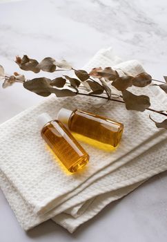 Natural cosmetics. Essential oil bottle mockup, plastic bottle with cosmetic product on white bath towels and eucalyptus leaves