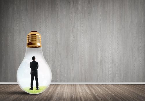 Businessman inside of light bulb in empty concrete room