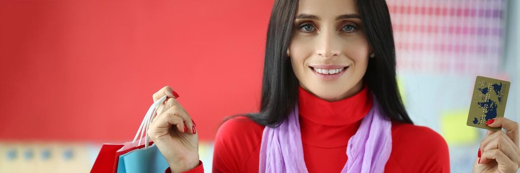 Young woman holds plastic credit card and shopping bags. Promotional offers for shopping concept