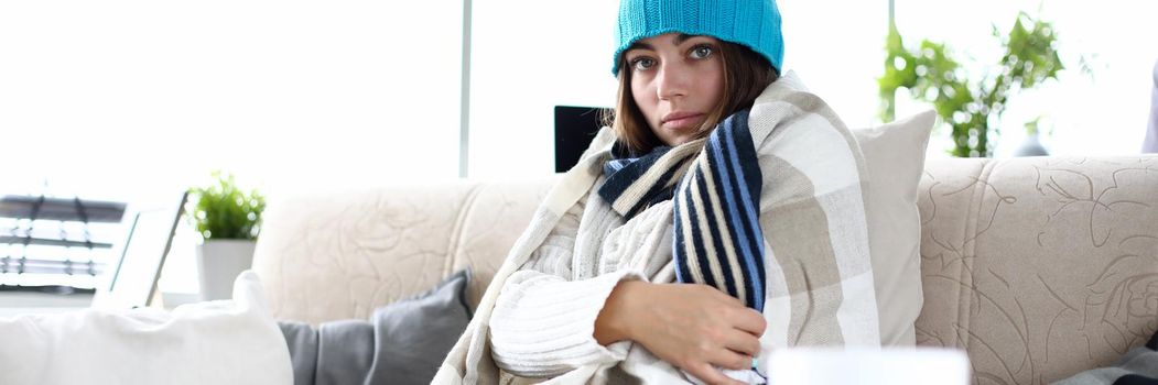 Young sad sick woman wearing hat and blanket. Fever causes methods of diagnosis and treatment