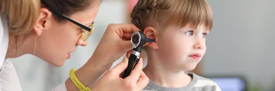 ENT doctor conducts physical examination of little girl ear. Hearing test in children concept