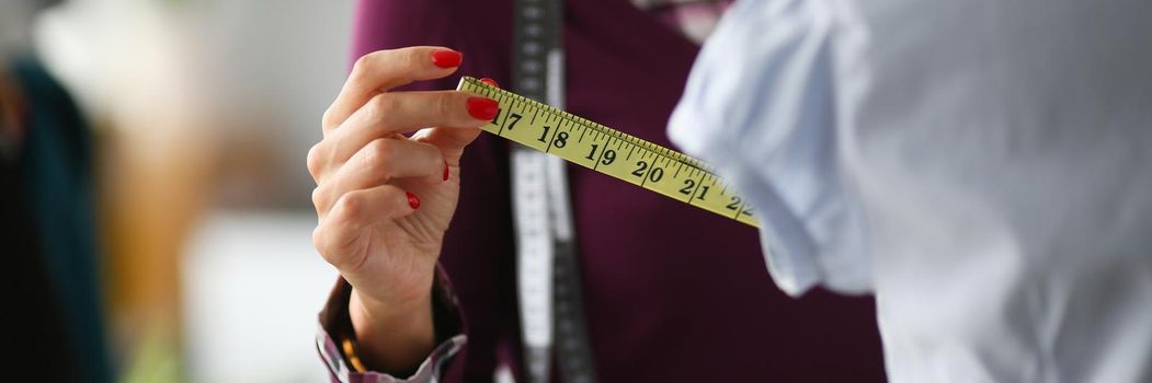 Woman fashion designer takes measurements with centimeter. Custom tailoring concept