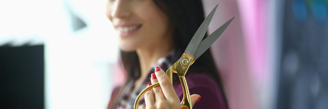 Young woman holds in hands professional seamstress scissors. Correct fabric cutting concept