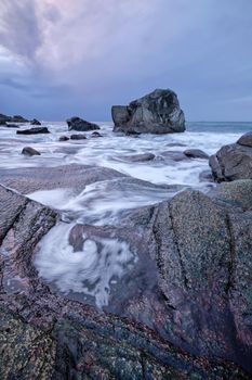 Rocks on beach of fjord of Norwegian sea in winter on sunset. Utakliev beach, Lofoten islands, Norway