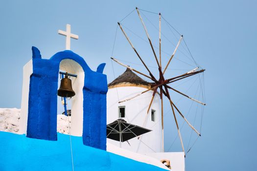 Old traditional whitewashed greek windmill and orthodox christian church bell on Santorini island in Oia town. Oia village, Santorini, Greece