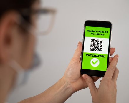 The doctor holds a smartphone with a QR code about the vaccination performed