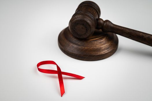 Judicial gavel and red ribbon on a white background. Symbol of the fight against AIDS