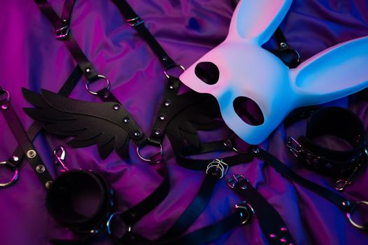 the rabbit mask and leather bdsm belts and accessories for bdsm games in neon light