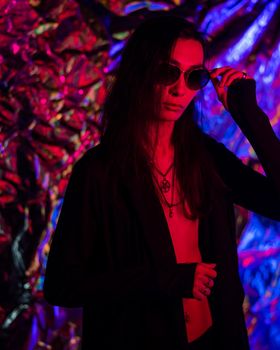 Portrait of a transgender model in sunglasses in a studio with neon lighting