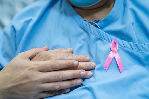 Breast cancer, pink ribbon at Asian senior lady patient for supporting awareness.