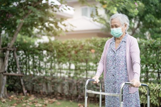 Asian senior or elderly old lady woman walk with walker and wearing a face mask for protect safety infection and kill Novel Coronavirus Covid-19 virus.