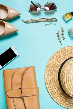 Flat lay, top view, mock up women's clothes and accessories on a turquoise background. Telephone, sunglasses, bracelet, straw