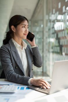 Confident business asian woman in talking consultant on mobile phone at modern office.