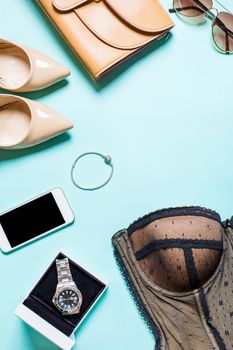 Flat lay, top view, mock up women's sexy clothes and accessories on a turquoise background. Telephone, sunglasses, bracelet