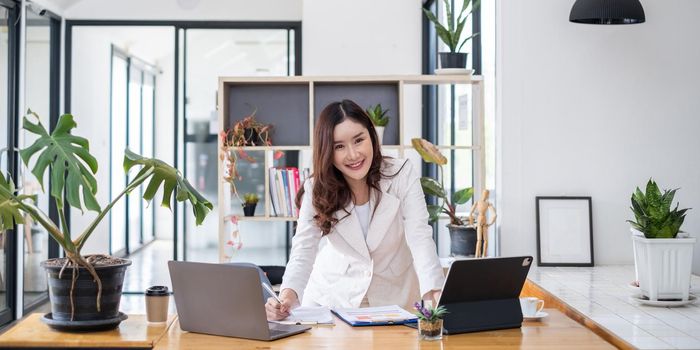 Business woman hand holding pen looking at bank savings account application on laptop. account or saving money or insurance concept