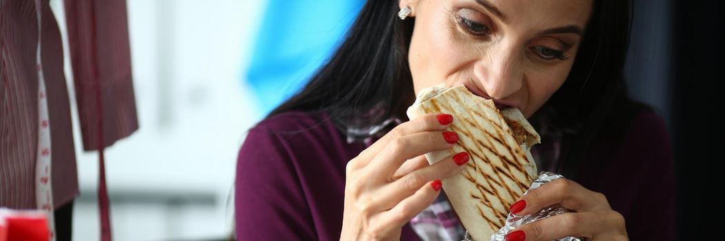 Young woman greedily shakes delicious shawarma. Shawarma recipe concept
