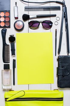 Flat lay, top view, mock up cosmetics and women's accessories. Green handbag, Phone, watch, pen, purse, curling on white background