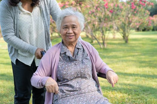 Caregiver help and care Asian senior or elderly old lady woman patient sitting and happy on wheelchair in park, healthy strong medical concept.