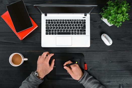 Hipster black wooden desktop top view, male hands typing on a laptop. Top view. Copy space