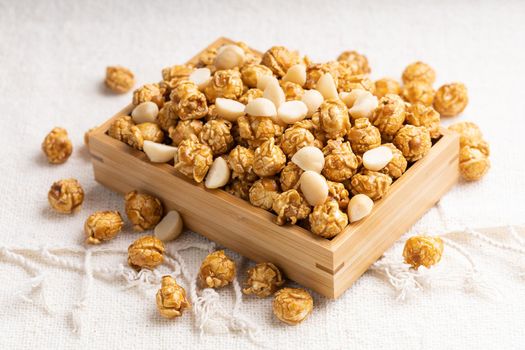 Golden color caramel popcorn with macadamia nut in bamboo wooden box, Crunchy and sweet dessert