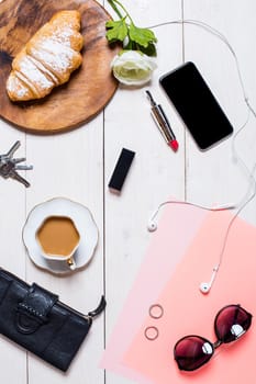 Flat lay, top view, mock up women's accessories on a white background. phone, croissant, a cup of coffee