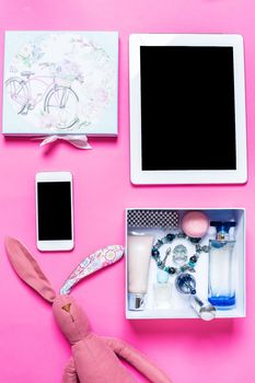 Flat lay, top view, mock up girl's accessories on a pink background. bracelet, rabbit, toy, perfume, phone, tablet