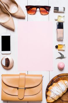 Flat lay, top view, mock up women's clothes and accessories on a white background. phone, shoes, perfume, sunglasses, croissant