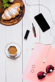 Flat lay, top view, mock up women's accessories on a white background. phone, croissant, a cup of coffee