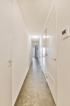 A long straight corridor in white with many doors and an entrance to a spacious apartment