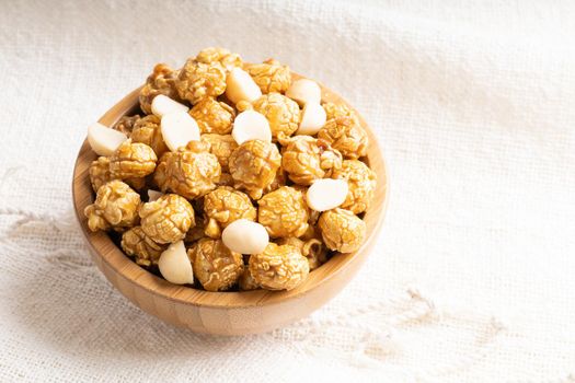 Golden color caramel popcorn with macadamia nut in bamboo wooden bowl, Crunchy and sweet dessert