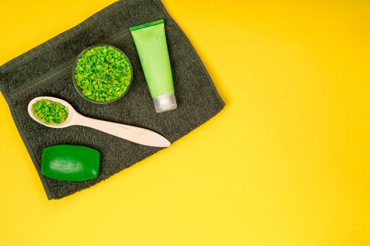 Spa set: soap, mask, oil, sea salt and towel on yellow background. Top view. Still life. Copy space