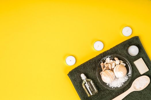 Spa set: soap, essential oil, sea salt and towel on a yellow background. Still life. Copy space