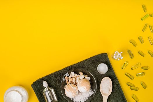 Spa set: soap, essential oil, sea salt and towel on a yellow background. Still life. Copy space