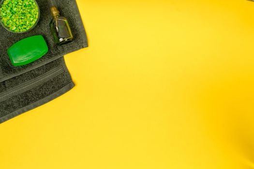 Spa set: soap, mask, oil, sea salt and towel on yellow background. Top view. Still life. Copy space