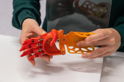 A woman demonstrates a plastic children's prosthetic hand printed on a 3D printer