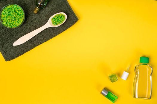 Spa set: soap, mask, oil, sea salt and towel on yellow background. Top view. Still life. Copy space