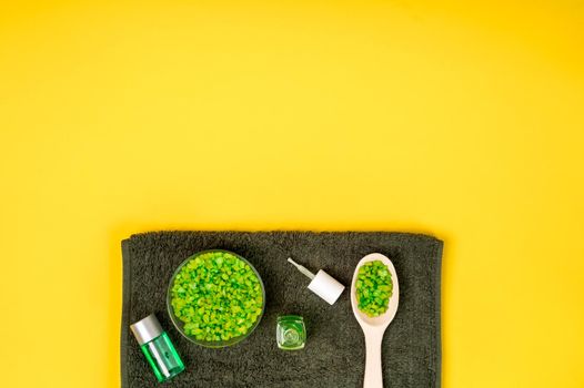 Spa set: soap, mask, oil, sea salt and towel on yellow background. Top view. Still life. Copy space