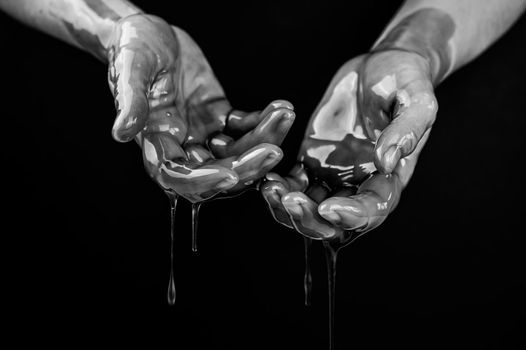 Women's hands in a viscous liquid similar to blood. Black and white photo